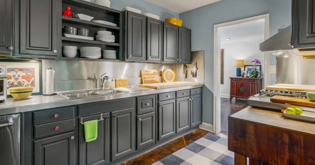 Kitchen with dark gray cabinetry, stainless steel backsplash, open shelving, and wood island in Atlanta, GA.