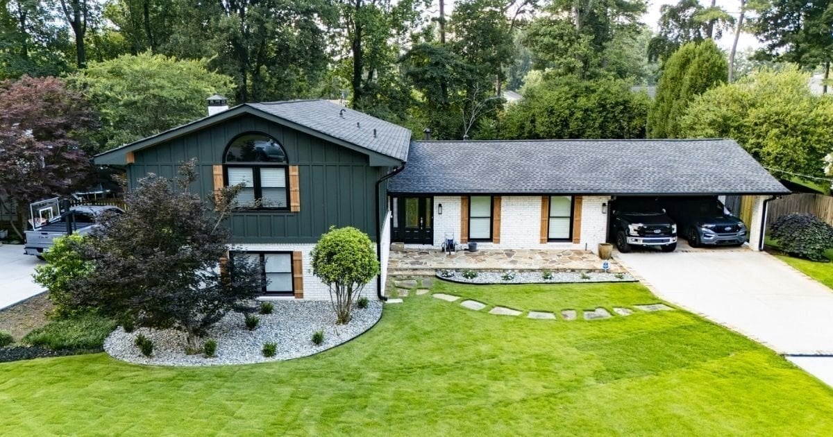 Dark green and white split-level home with wood accents, landscaped front yard, and attached carport in Atlanta, GA.
